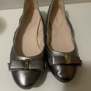 Cole Haan silver flat shoes with bow and logo on the front